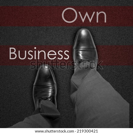 A business man is looking down at his feet with a red race line that says Own Business