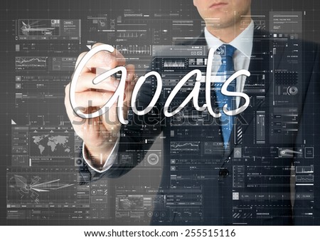 the businessman is writing Goals on the transparent board with some diagrams and infocharts