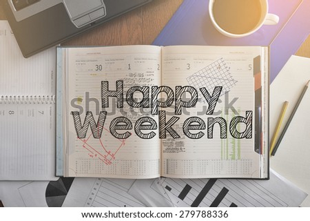 Notebook with text inside Happy Weekend on table with coffee, some diagrams on paper and laptop