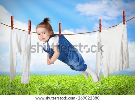 Funny child hanging on line with clothes, laundry creative concept