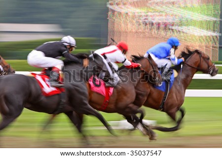 Slow shutter speed rendering of three racing jockeys and thoroughbreds