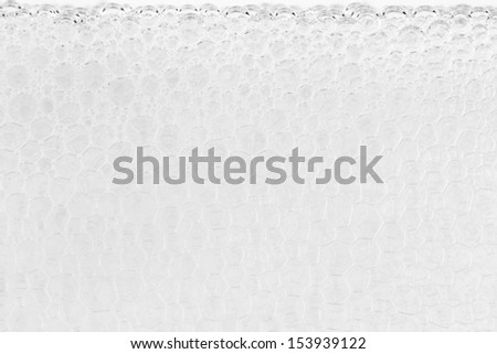 Close up of clear soap suds against glass forms geometric shapes.