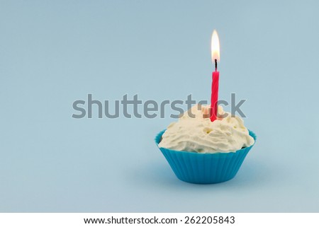 Happy birthday cupcake with pink burning candle on blue background