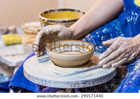 Female hand with clay plate with pattern on a pottery wheel