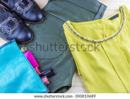 Top view of fashion women's set: retro shoes, blouse, pants and cosmetics on wooden background