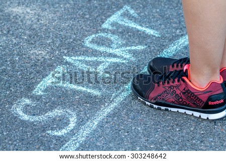 Kiev, Ukraine - August 04, 2015: Sport woman in Reebok sneakers getting ready to run near the start line
