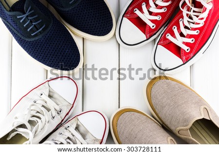 Top view of different colorful men's shoes in the circle on white wooden background
