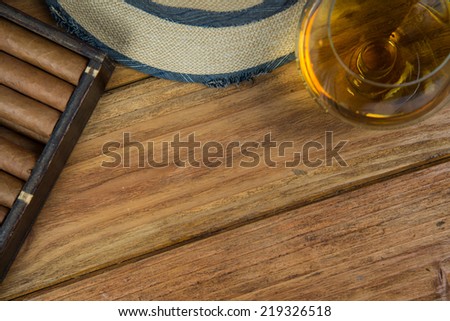 Cuban cigars and Rum or other alcohol in glass on table top view with vintage wooden background and copy space