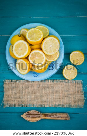 Market fresh organic lemons halves on wooden table background with copy space and juice squeezer