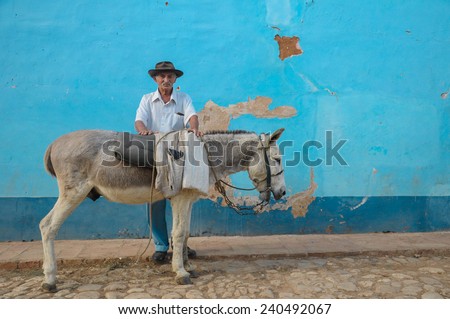TRINIDAD, CUBA - DECEMBER 28, 2013: Old local man and donkey on street in Trinidad, Cuba. Donkeys are use as taxi for tourist in this UNESCO listed city.