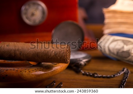 Rich person desk with cuban cigar, dollar notes and expensive watch