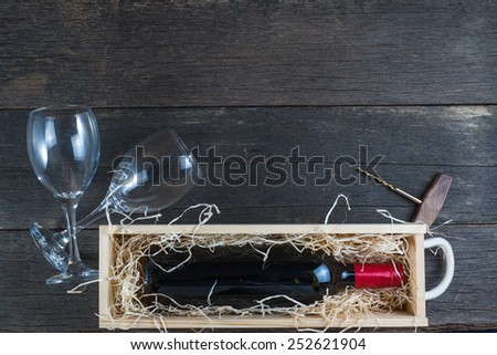Wine in wooden case with straw and glass from above