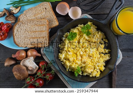 scrambled eggs with toast, top view on wooden table