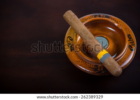 Cuban cigar in ash tray  isolated on wooden bar