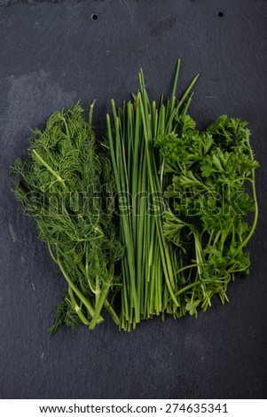 Spring garden fresh chives,parsley and dill on black slate  background