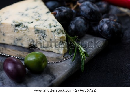Marble board with cheese selection, wine and grapes on dark background from above