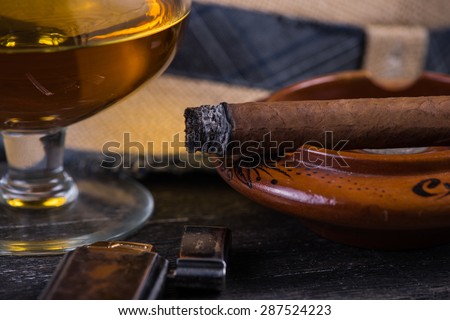 Cuban cigar,straw panama hat and lighter on wooden table