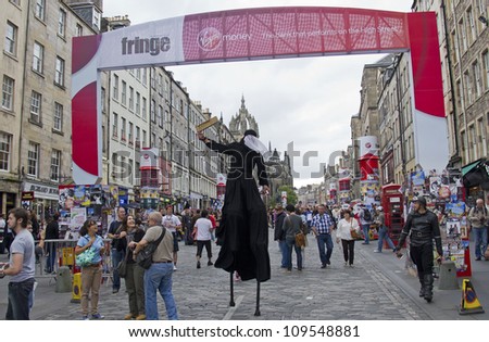 EDINBURGH, UK: AUGUST 2: Stilt walker passes under the Fringe Gate on the Royal Mile, the main street of Edinburgh, at the Edinburgh Festival Fringe on August 2, 2012 in Edinburgh.