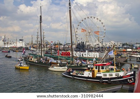 Amsterdam, Holland - August 21, 2015: People on many kinds of boats pass the I Amsterdam logo and the giant ferris wheel during the Sail event in Amsterdam, Holland on August 21, 2015.