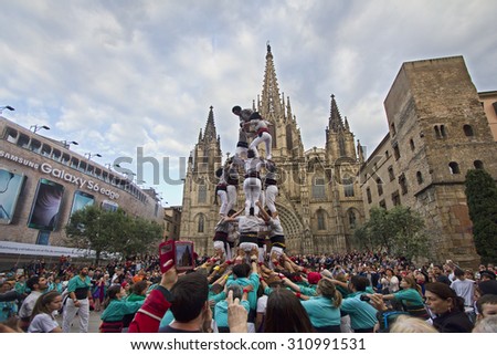 BARCELONA - MAY 23, 2015: People building a human tower, called castelling, among a large crowd of people in front of the cathedral of Barcelona, Spain on May 23, 2015.