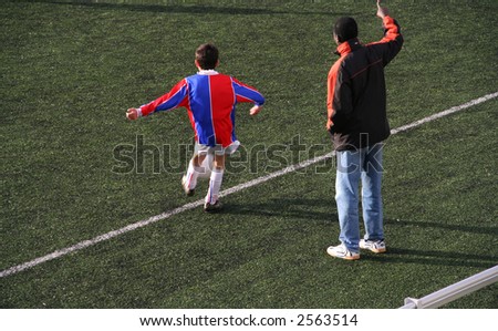 Kid takes a corner in a soccer match while his coach is coaching