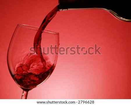Red wine pouring into the glass over red background