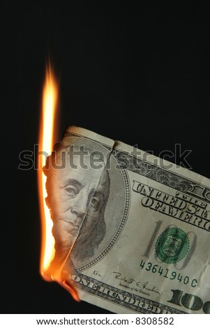 One hundred dollars bill on fire over black background