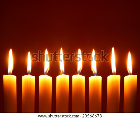 Eight alight candles close-up over red background