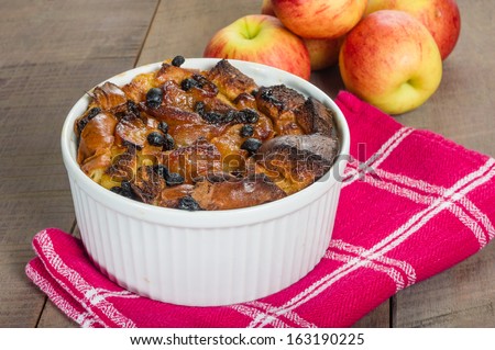 Apple bread pudding with raisins baked in white bowl