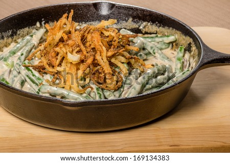 Fried onions cooking with beans in a cast iron skillet
