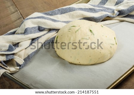 Artisan rosemary bread rising on a sheet pan