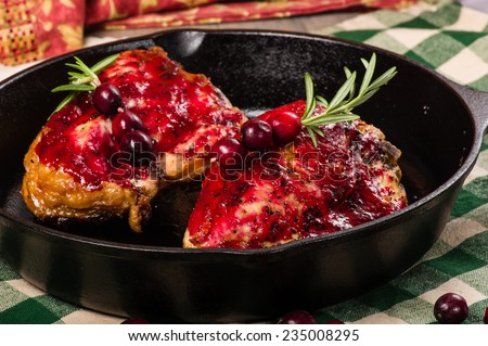 Two cranberry glazed chicken breasts in a cast iron skillet