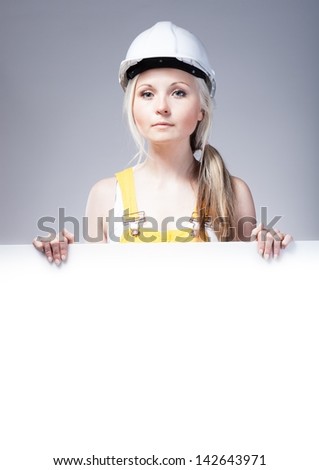 Young builder woman construction worker and empty poster