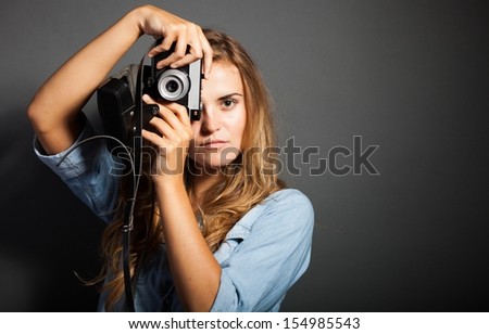 Hot photographer woman in jeans jacket taking pictures with old camera
