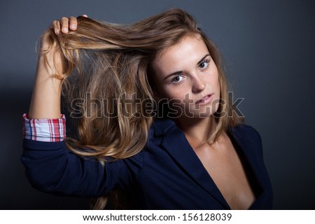 Sexy woman pulls hair on dark background