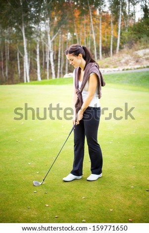 Young woman golf player training on green with club
