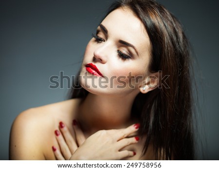 Natural woman face with red nails and lips on dark background