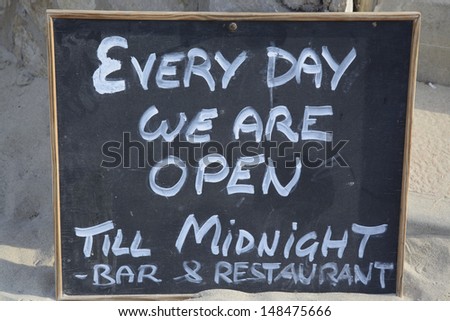 Open sign in blackboard and white chalk saying 'every day we are open till midnight'.