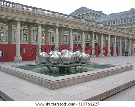 PARIS, FRANCE - JANUARY 2, 2010: Royal castle courtyard with shiny steel ball sculpture and people watching on January 2, 2010 in Paris, France.