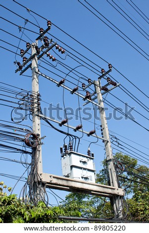 electrical post by the road with power line cables, transformers and phone lines