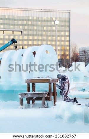 PERM, RUSSIA - DEC 17, 2013: Man carves sculpture with big circles in Ice town. Construction of ice town worth 268,000 dollars