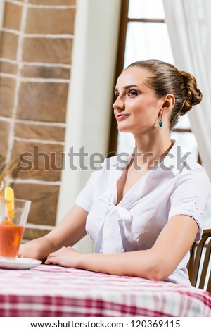 portrait of a nice lady in a restaurant, sitting with one cocktail at the table and waiting