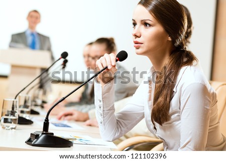 Business woman speaks into a microphone, communication businessmen at a conference