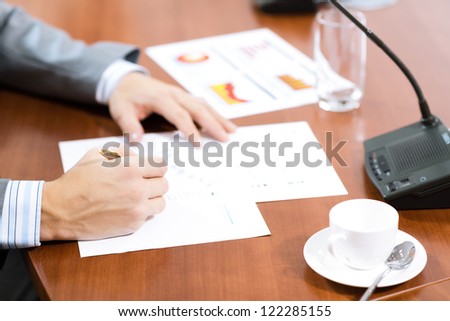 Businessman writing on paper notes, On the table is a cup of coffee and a device for communication at the conference