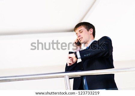 Businessman talking on cell phone and looking at his watch