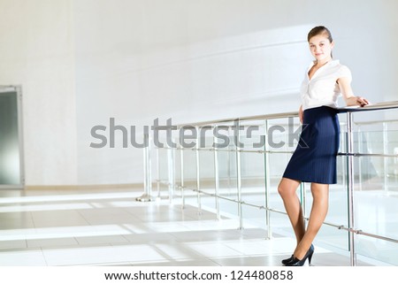 Business woman standing in the lobby of the office, based on the railing of the balcony