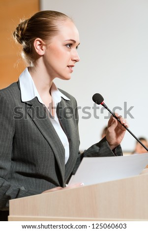 Portrait of a business woman holding a microphone and looks ahead