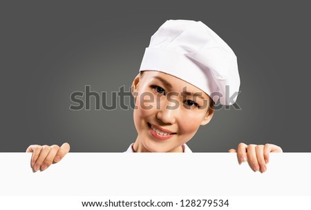 female chef holding a poster for text, look at the camera and smiling
