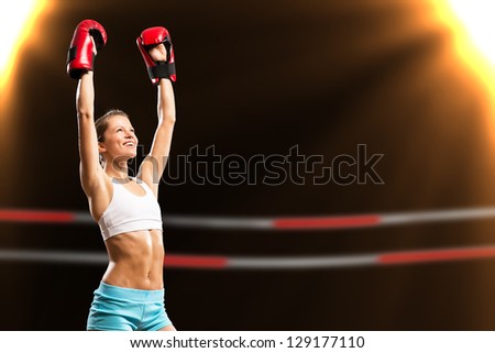 female boxer is in the rays of lights, raised a hands in a gloves