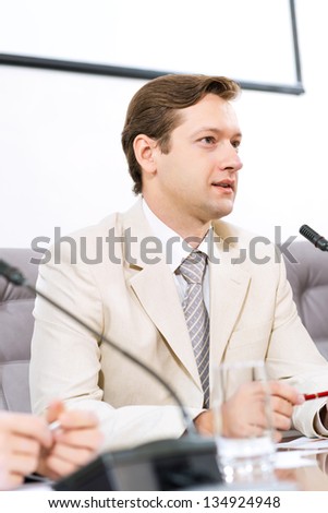 Portrait of a businessman, said into the microphone, the meeting